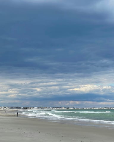 Wide open Atlantic beach with dramatic clouds and gentle surf along the Cape Cod shoreline