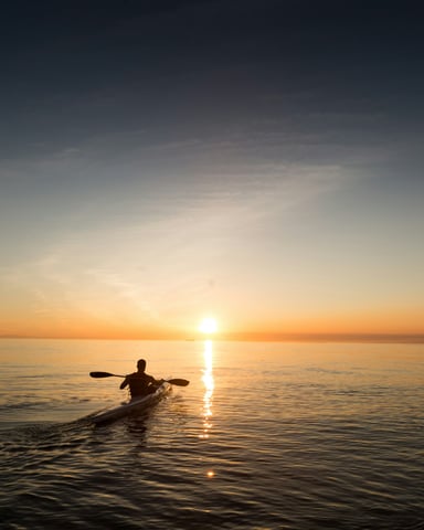Kayaker at sunset on calm water