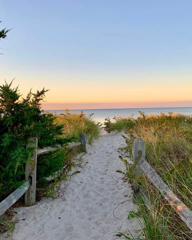 Sandy dune path through beach grass at golden hour leading toward the ocean