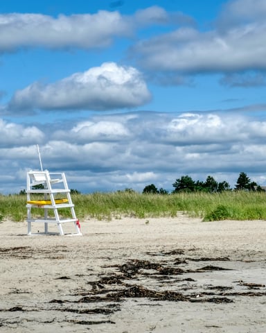 Lifeguard stand on a wide sandy New England beach under a partly cloudy summer sky