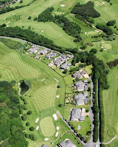 Aerial view of a golf resort with condos and homes nestled among lush green fairways and trees