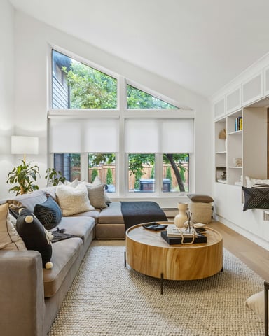 Bright open-plan living room with vaulted ceiling, large windows, and warm natural light