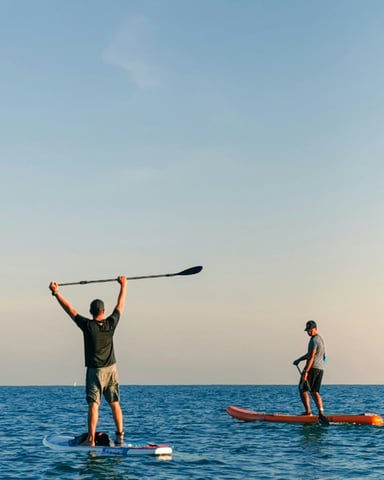 Paddleboarders on calm ocean at dusk
