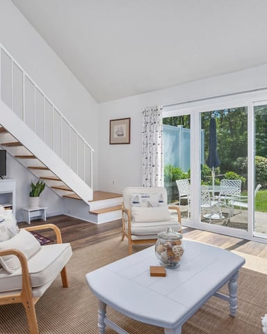 Bright nautical living room with straight staircase, sailboat curtains, and garden patio doors