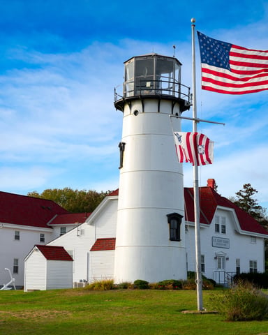 Chatham lighthouse with US Coast Guard station and American flag against a blue sky