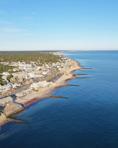 Aerial view of Cape Cod coastline with town, beach, and calm blue ocean