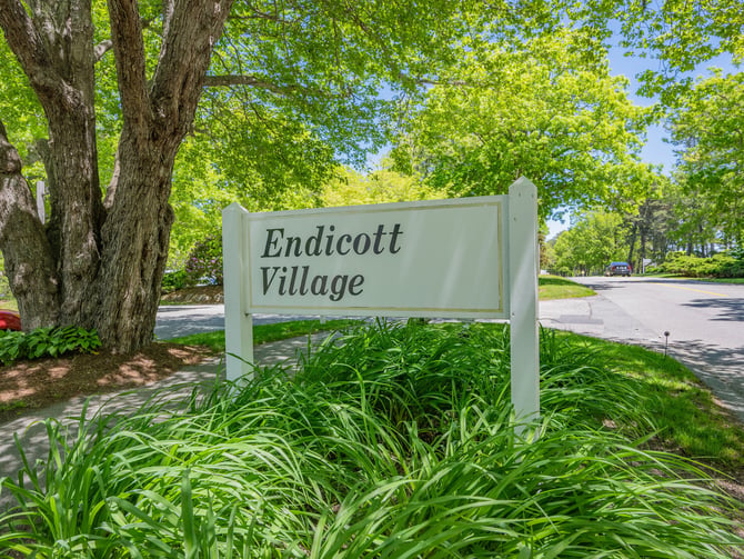 Endicott Village entrance sign surrounded by lush summer trees at Ocean Edge